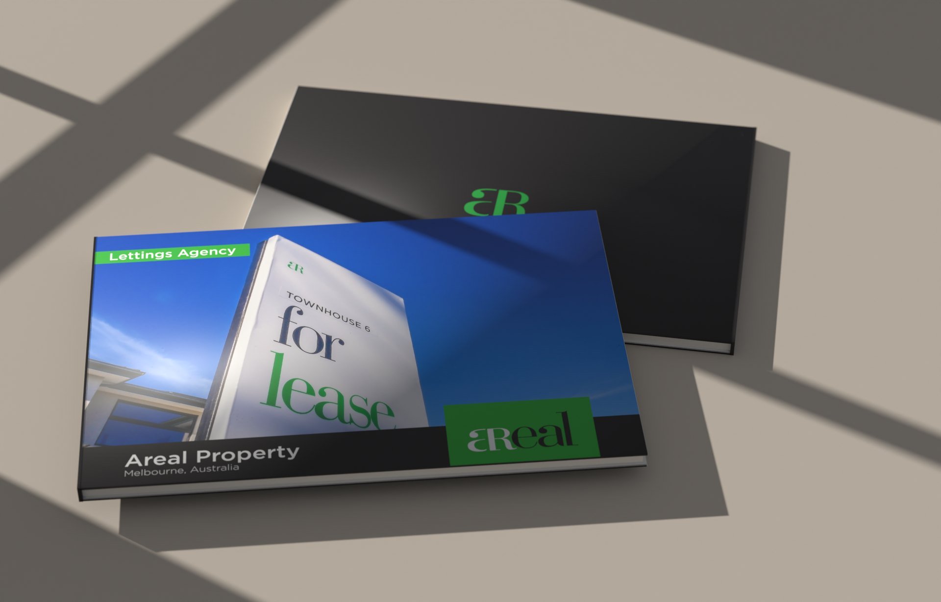 Areal's two brochures on a warm stone backdrop under window light: the Letting Agency brochure, with a for lease sign on its cover, over the dark corporate portfolio with the green monogram